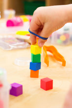 Load image into Gallery viewer, Child&#39;s hand stacking blocks with a rubber band around fingers

